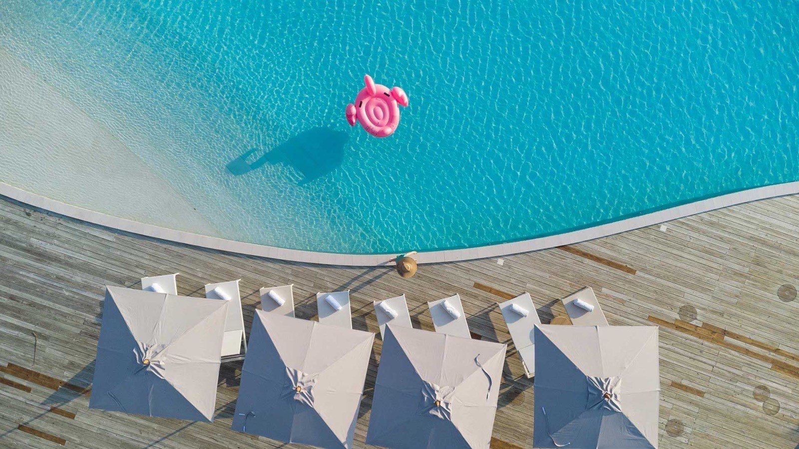 The resort's main pool with loungers and parasols beside the beach.